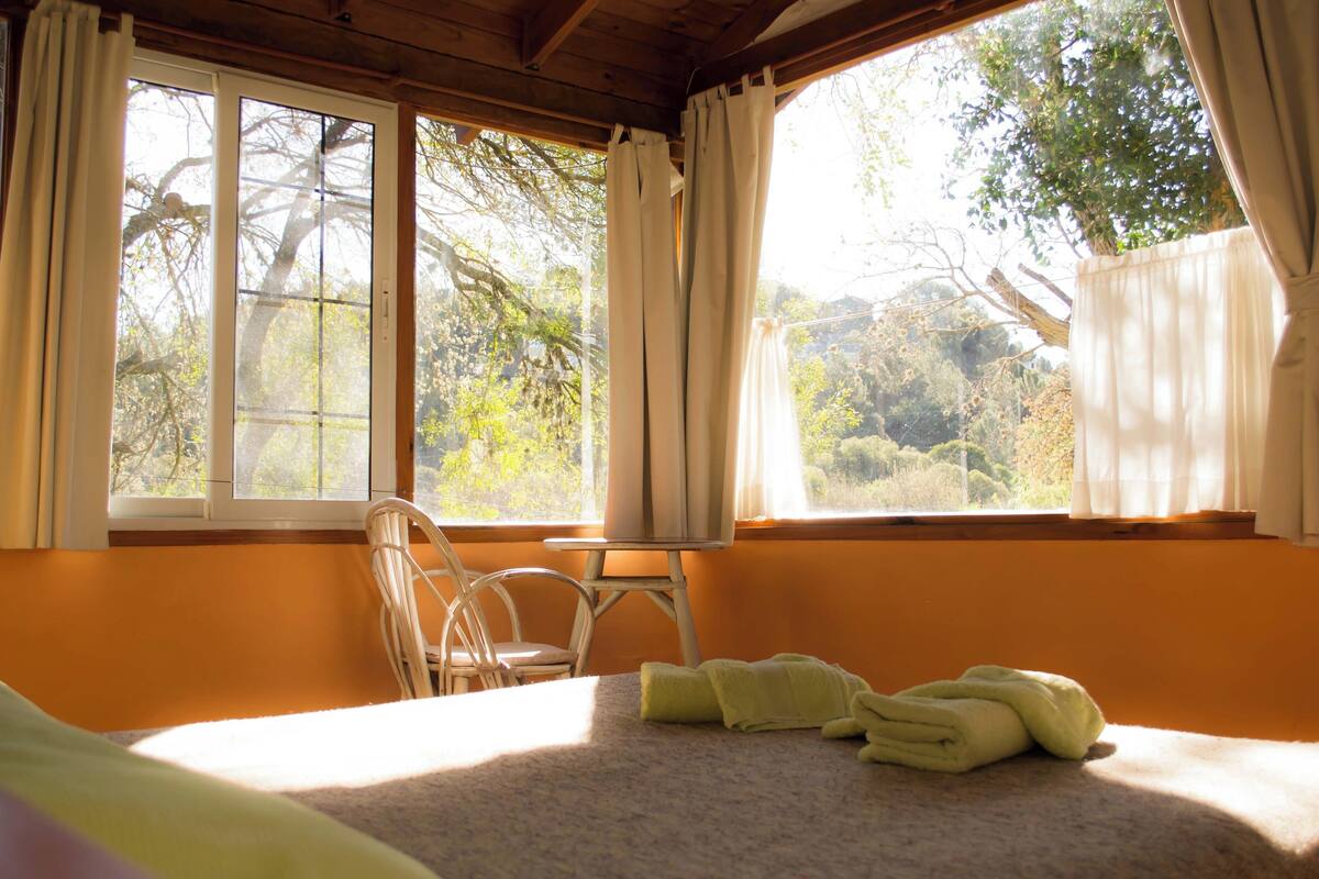 Une pièce avec un lit, une chaise et une fenêtre avec des rideaux.