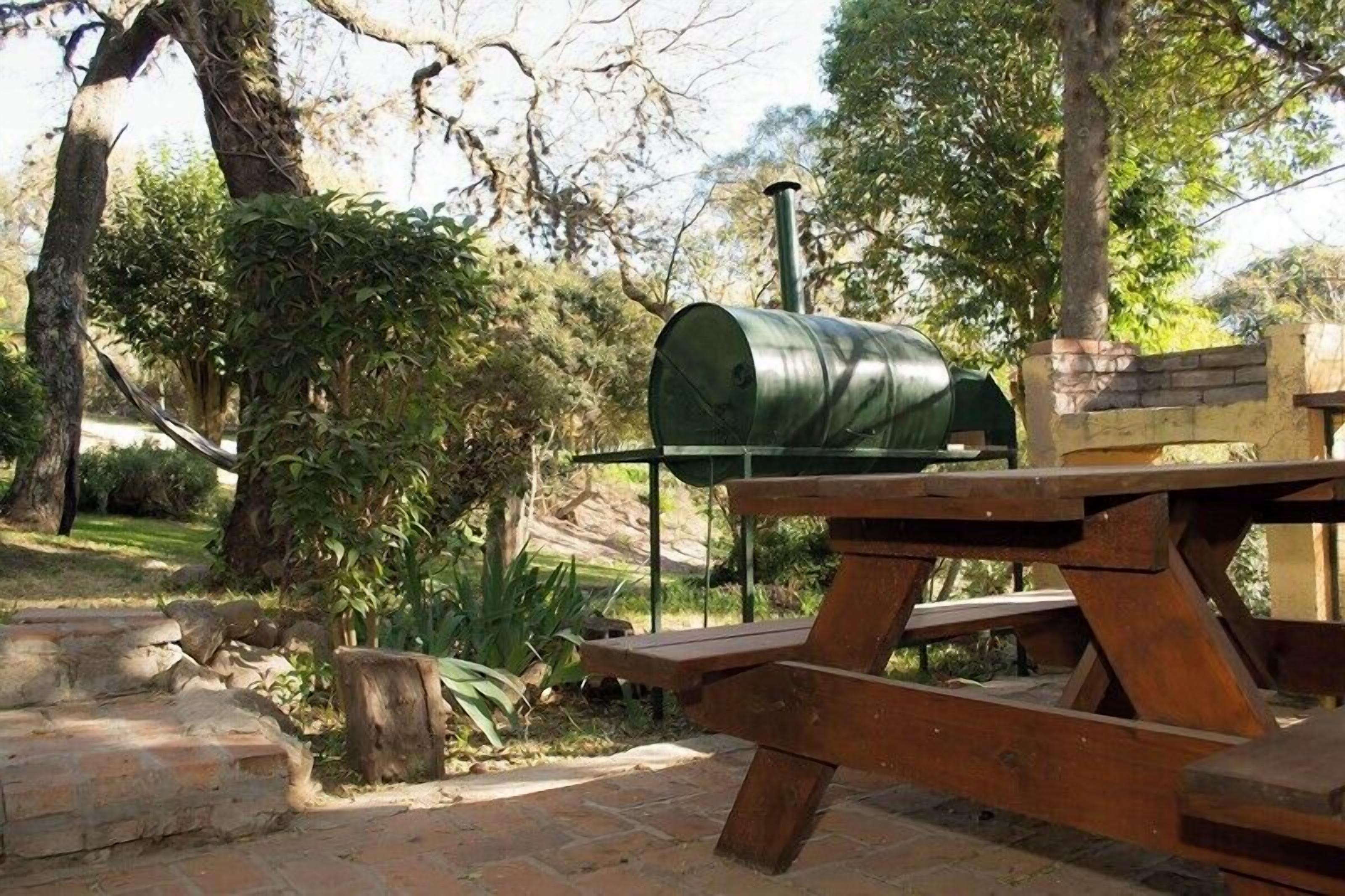 Una mesa de picnic con un barril verde y un banco de piedra en un jardín.