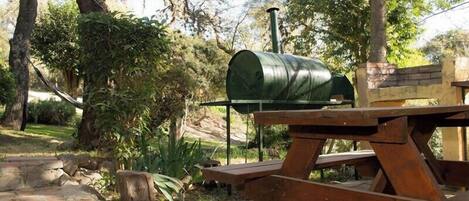 Una mesa de picnic con un barril verde y un banco de piedra en un jardín.