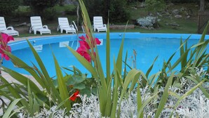 A swimming pool surrounded by white lounge chairs, with a wooden cabin in the background. - Apart Suites & Cabañas Duendes del Pungo (La Cumbre)