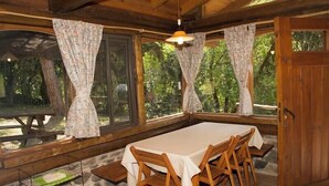 A dining area with a long table, wooden chairs, and patterned curtains. - Apart Suites & Cabañas Duendes del Pungo (La Cumbre)