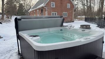 A hot tub with a wooden exterior, positioned outdoors with snow on the ground.