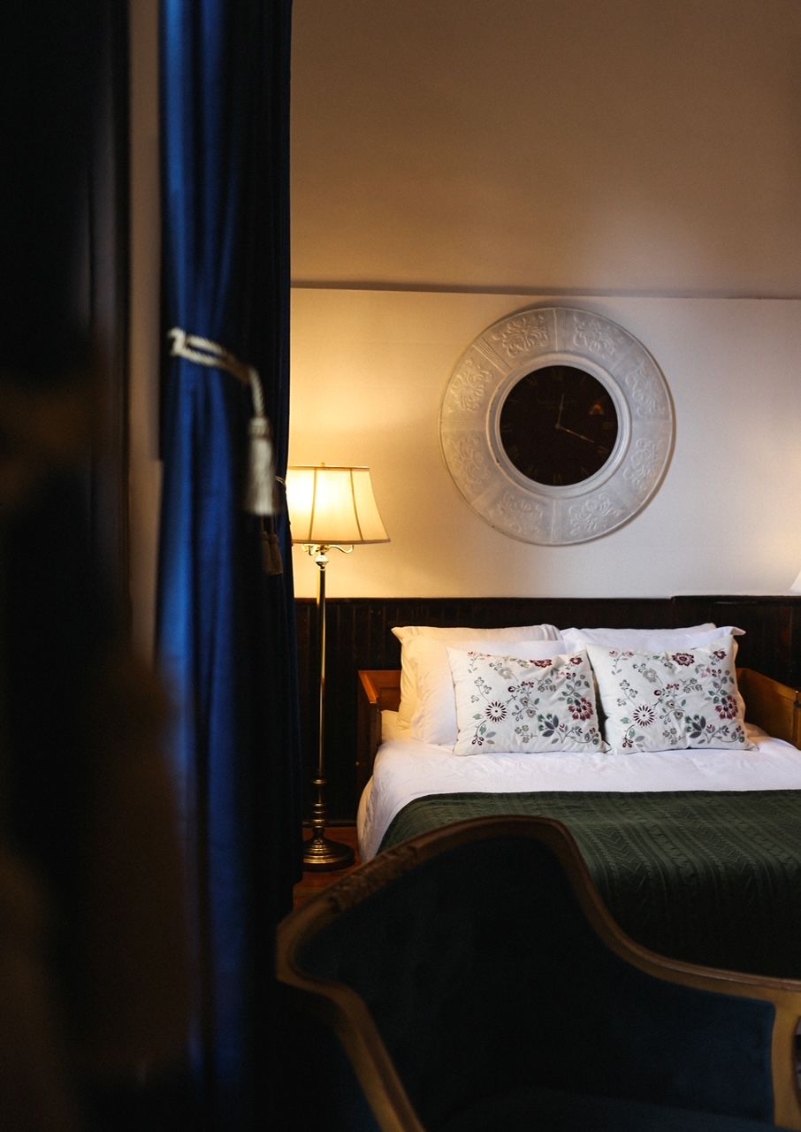 Een hotelkamer met een bed, een ronde wandklok en een lamp.