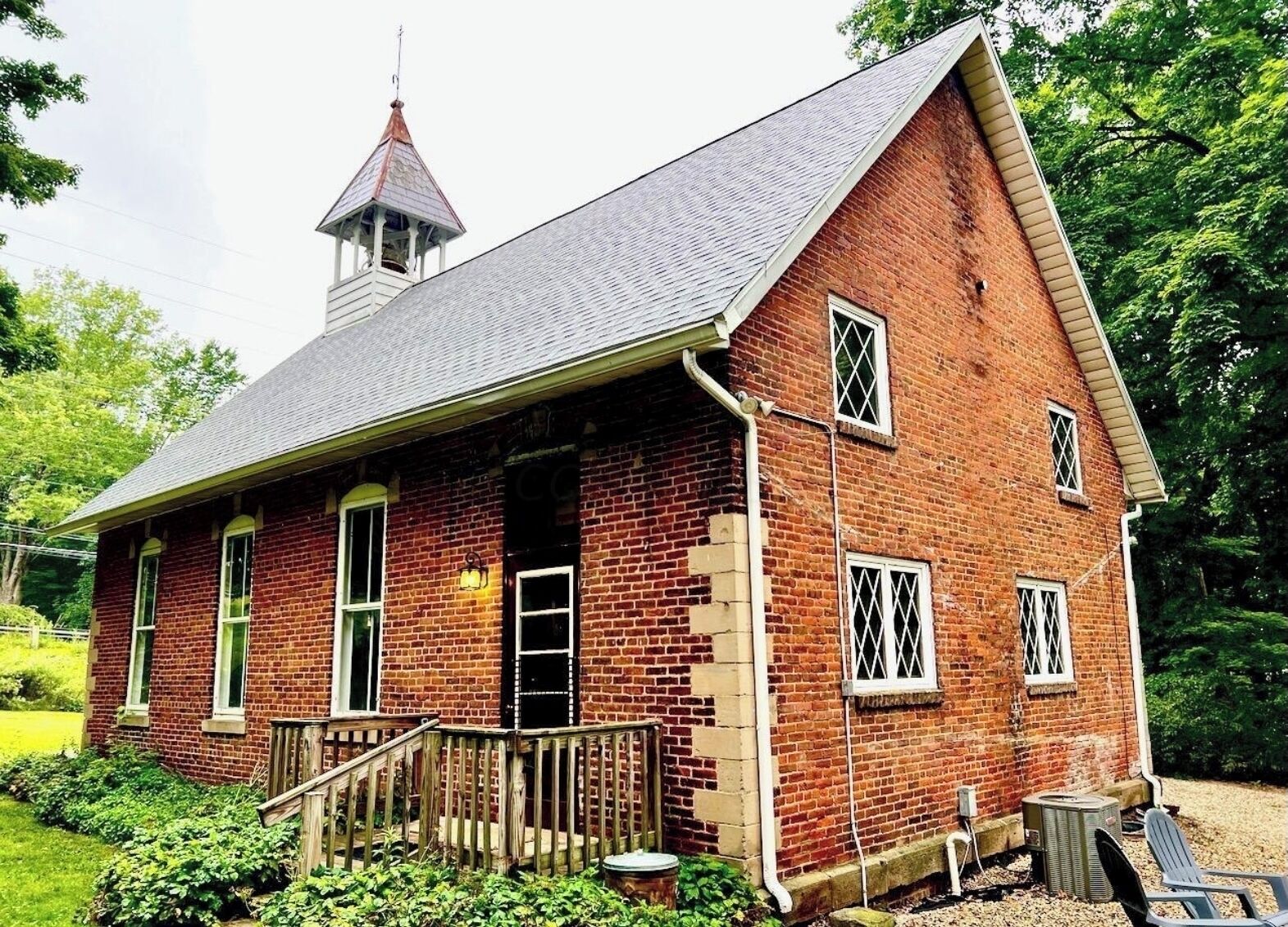 A red brick building with a steeply pitched roof and a small tower.