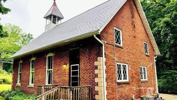 A red brick building with a steeply pitched roof and a small tower.