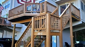 A two-story house with a wooden deck and a staircase. - Lake Loft at Deep Creek Lake (Oakland)