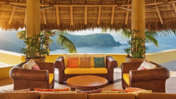 A thatched-roof outdoor seating area with a view of the ocean and hills. - Sol de Oriente (Costa Careyes)