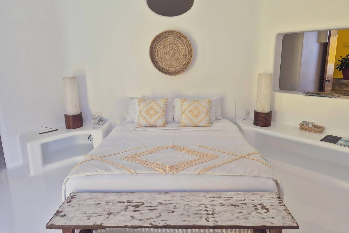 A modern bedroom with a large bed, two bedside tables, a round wall decoration, and a mirror.