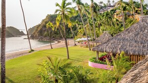 A beachside resort with thatched-roof huts, a grassy lawn, and a view of the ocean. - Sol de Oriente (Costa Careyes)