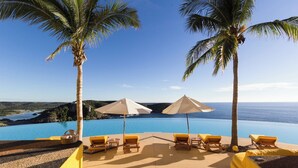 A poolside area with lounge chairs and umbrellas, overlooking a clear blue ocean and distant hills. - Sol de Oriente (Costa Careyes)