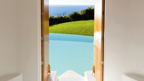 A doorway leading to a pool with a clear view of the ocean and a grassy area. - Sol de Oriente (Costa Careyes)