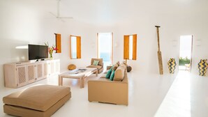 A modern living room with a flat-screen TV, a sofa, a coffee table, and a large window overlooking the sea. - Sol de Oriente (Costa Careyes)