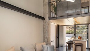 A modern living room with a sofa, a coffee table, and a kitchen area visible through an open door.