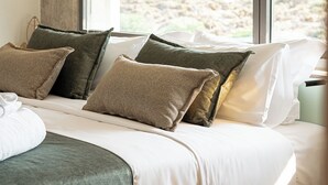 A bed with a wooden frame, white bedding, and multiple pillows.