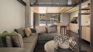 A modern interior with a sectional sofa, a glass dining table, and a kitchen area.