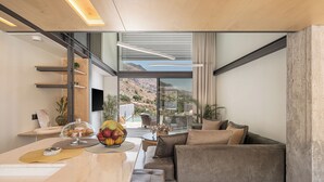 A modern kitchen with a marble countertop, a fruit bowl, and a dining area with a sofa and chairs.
