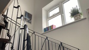 A staircase with a metal railing, a window with a potted plant, and a shelf with books. - Slough - Sleeps 3 - Petfriendly - Riverside - Bay (Slough)