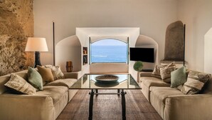 A living room with a view of the sea, a sofa, a coffee table, and a lamp. - Villa Fortino by MyVillaCollection (Maiori)