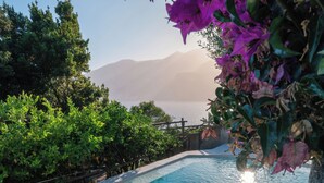 A clear pool with steps leading down to it, surrounded by greenery and a mountain in the background. - Villa Fortino by MyVillaCollection (Maiori)
