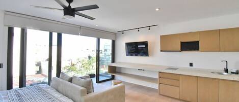 A modern bedroom with a large bed, a sofa, and a ceiling fan.