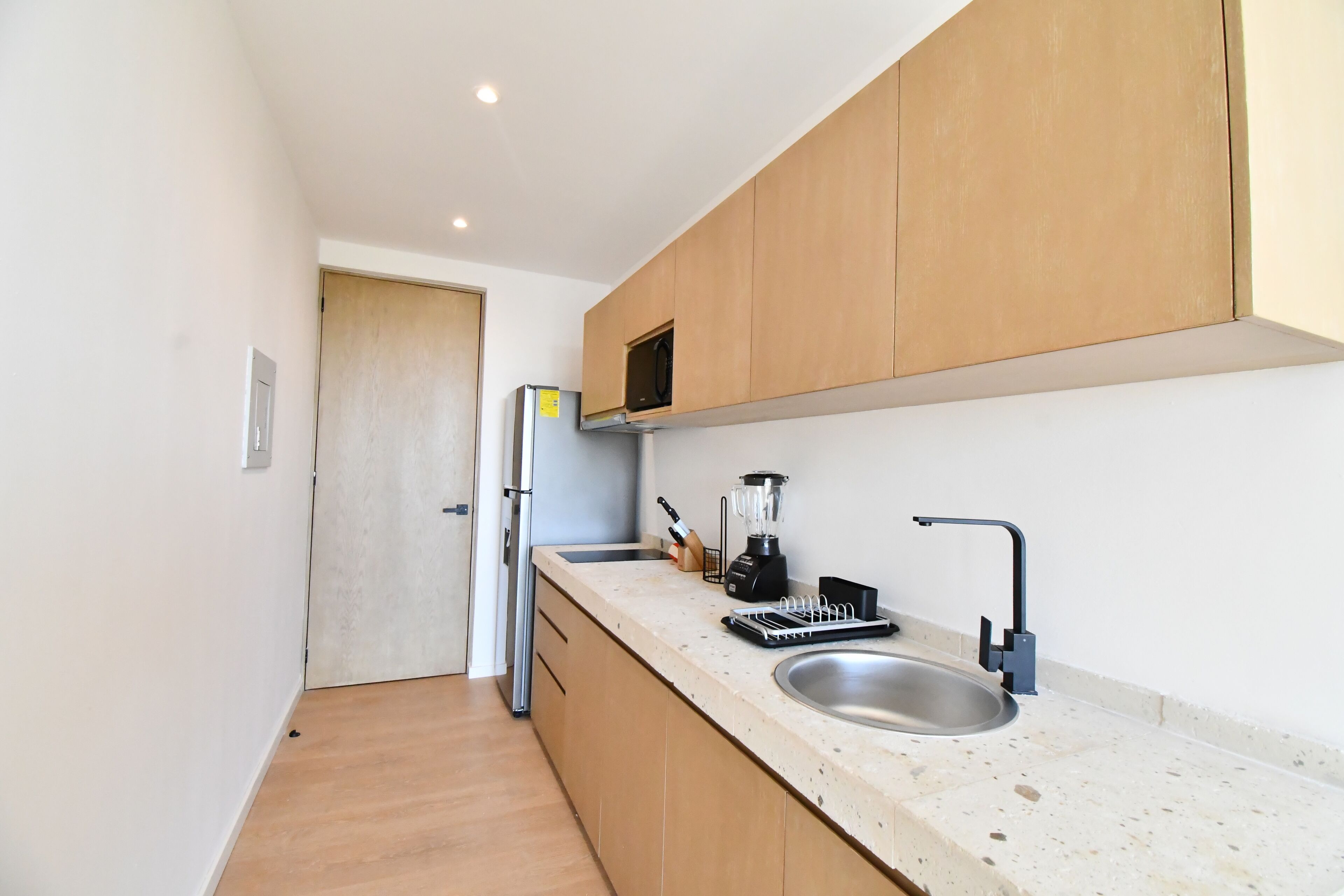 Eine moderne Küche mit Holzausbau, einer Edelstahl-Spüle, einem Einbauofen und einem Mixer auf der Arbeitsplatte.