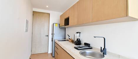 Eine moderne Küche mit Holzausbau, einer Edelstahl-Spüle, einem Einbauofen und einem Mixer auf der Arbeitsplatte.