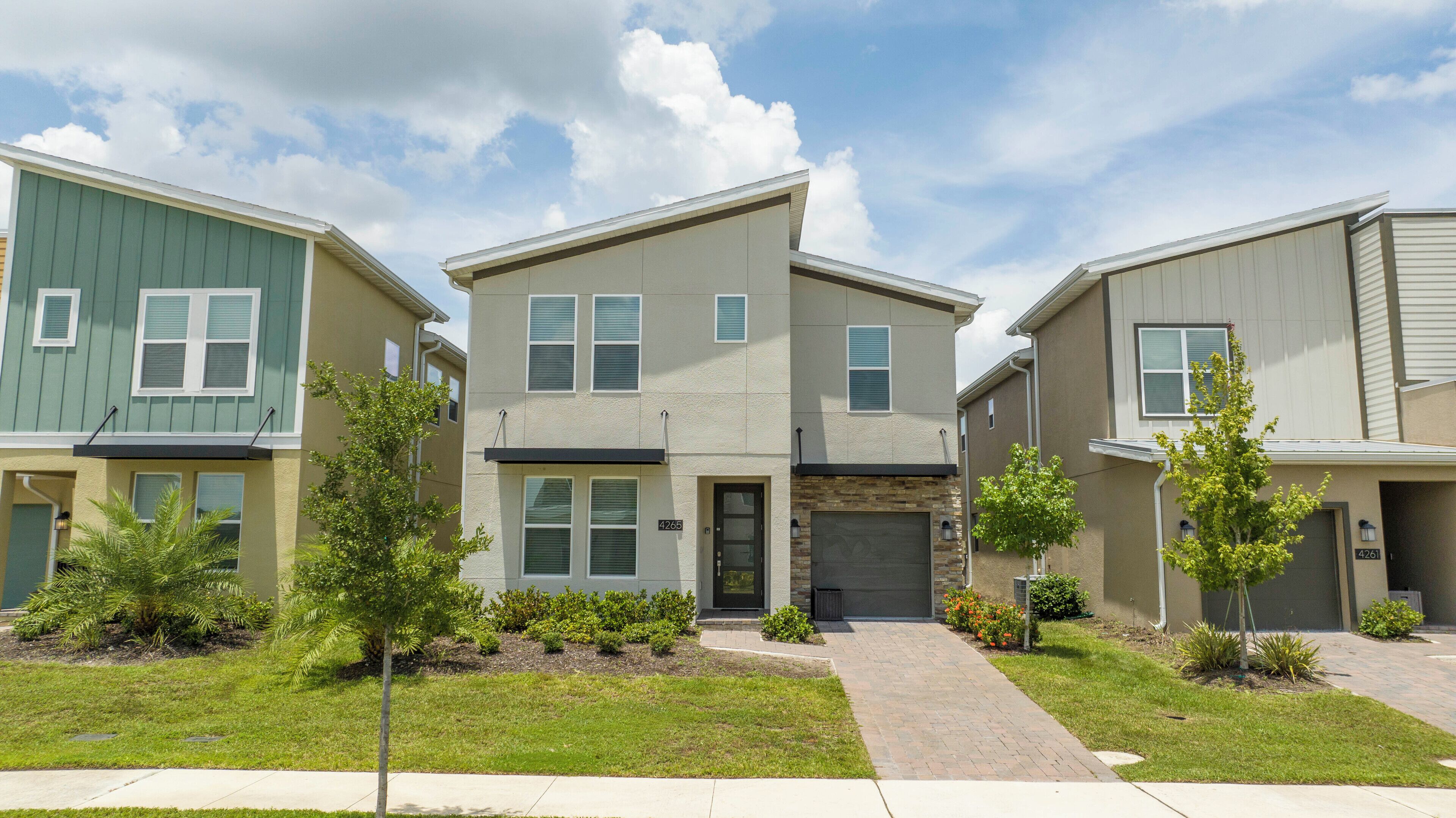 A row of townhouses with a central garage, small front yards, and a clear sky.