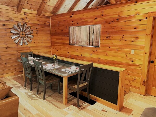 A wooden interior with a dining table set for four, surrounded by chairs.