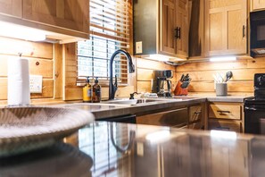 A modern kitchen with wooden cabinetry, a stainless steel sink, and a coffee maker.