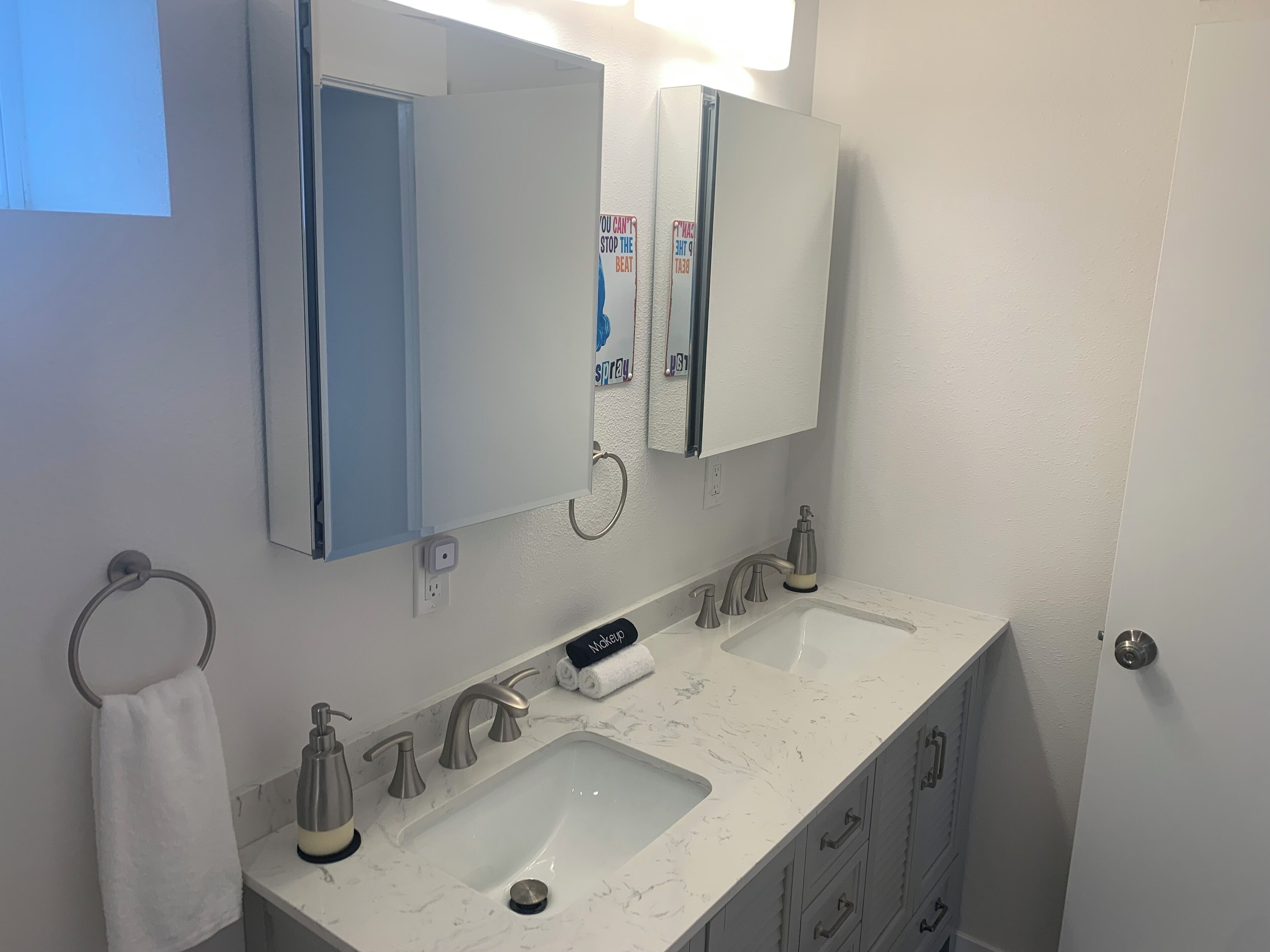 Een badkamer met twee wasbakken, een spiegel en een handdoekhouder.