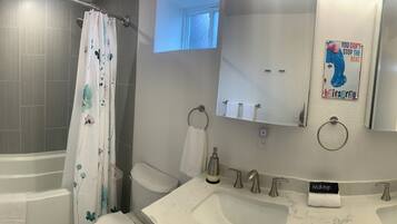 Une salle de bain moderne équipée d’une douche, de deux lavabos, d’un miroir et d’un porte-serviettes.