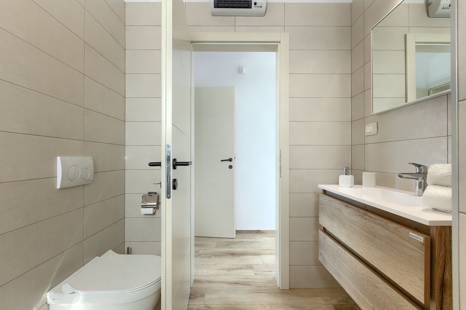 A modern bathroom with a toilet, sink, and mirror.