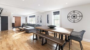 A spacious living area with a wooden dining table, benches, and a modern black chair. - ALL NEW, walk to North Conway Village + Railroad, fire pit (Conway)