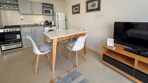 Una cucina moderna con un tavolo da pranzo e sedie, un televisore su un supporto in legno e un forno a microonde sopra il piano cottura.