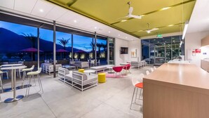 A modern indoor space with seating areas, a reception desk, and large windows. - Sophisticated Resort/WFA Amenity-Filled PS Home (Palm Springs)