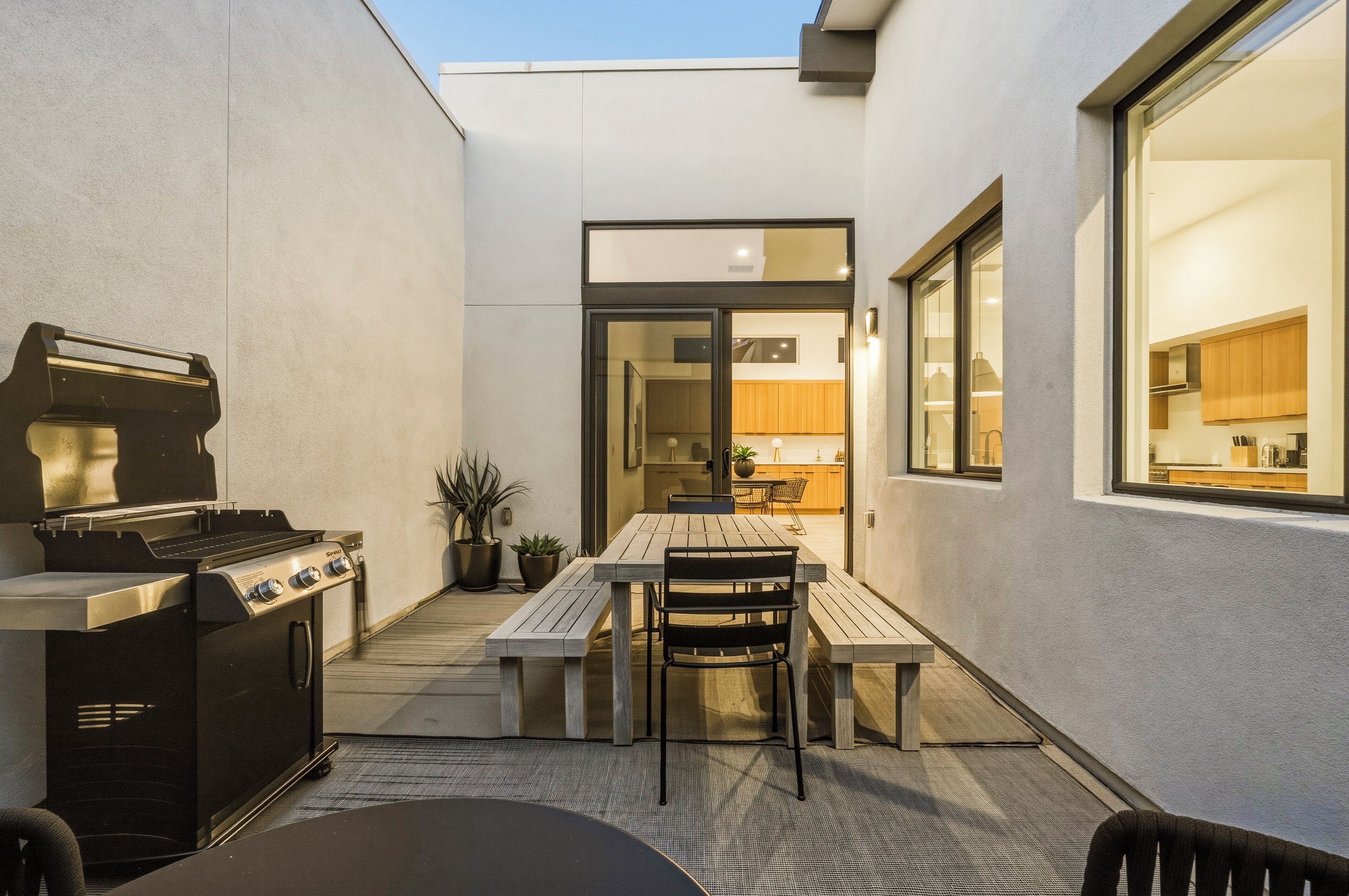 A patio with a grill, a table, and chairs.