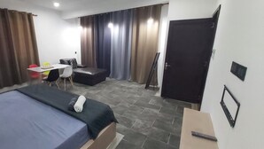 A hotel room with a bed, a desk, a chair, a sofa, and a wardrobe.