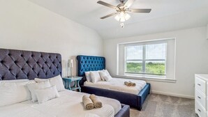 Een slaapkamer met twee bedden, een plafondventilator, een raam met uitzicht en een dressoir.