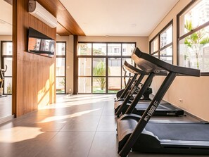 A gym with treadmills, a TV, and large windows. - Xtay Vila Madalena (São Paulo)