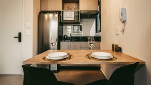 A compact kitchen with modern appliances, a dining table with chairs, and a phone on the wall. - Xtay Vila Madalena (São Paulo)