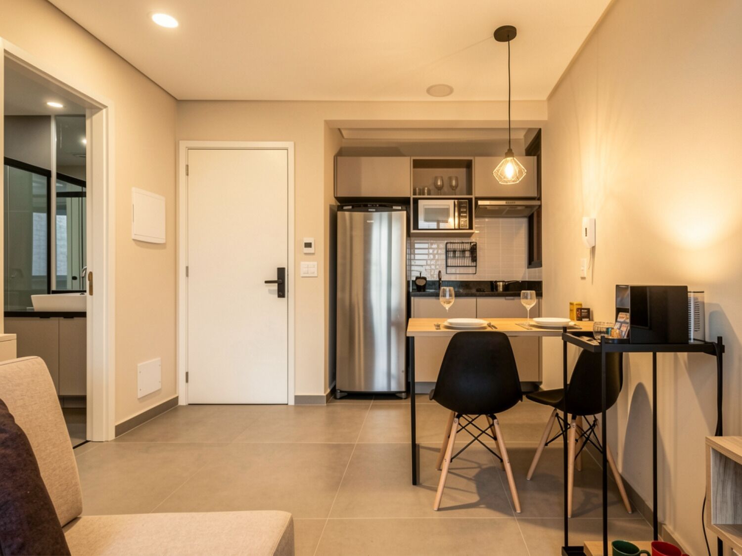 A modern kitchen with a refrigerator, microwave, and dining area with chairs and a table.