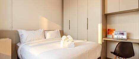 Una habitación de hotel moderna con una cama, un escritorio con una computadora portátil y una silla.