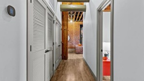 A narrow hallway with lockers on one side and a kitchen area visible through an open door. - Downtown Riverfront Loft Steps from Arch (St. Louis)