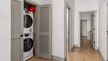 Un pasillo con un cuarto de lavado que incluye dos lavadoras y una secadora.