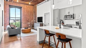 Una cocina moderna con armarios blancos, una isla grande y taburetes de bar.