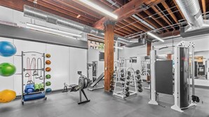 Een sportschool met diverse fitnessapparatuur, waaronder krachtapparaten en losse gewichten.