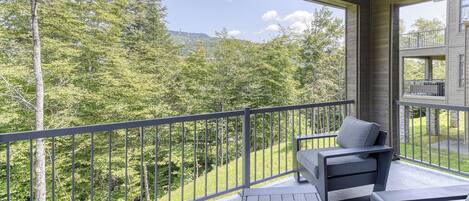A balcony with a view of a forest and a mountain.