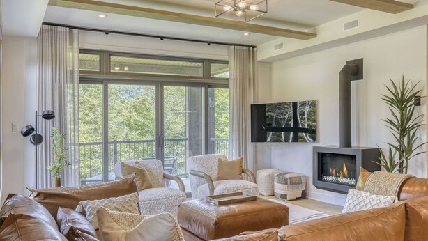 A modern living room with leather sofas, a fireplace, and large windows. - 101 Verbier Building 5 (Mont-Tremblant)