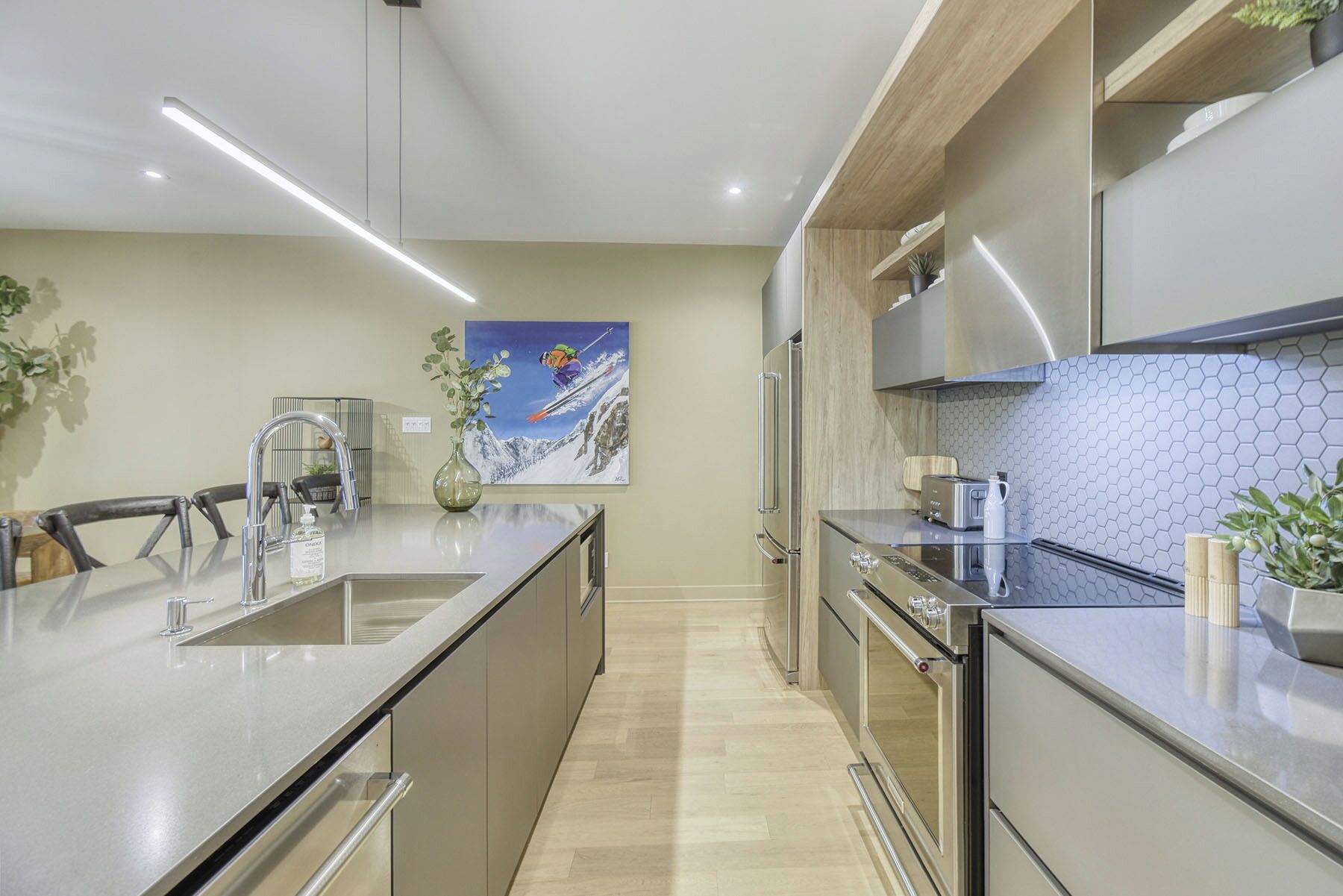 A modern kitchen with a central island, stainless steel appliances, and a hexagonal tile backsplash.