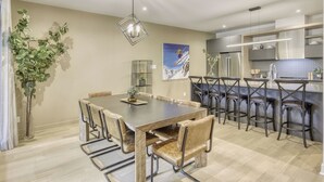 A modern kitchen with stainless steel appliances, a bar area with stools, and a dining area with a wooden table and chairs. - 101 Verbier Building 5 (Mont-Tremblant)